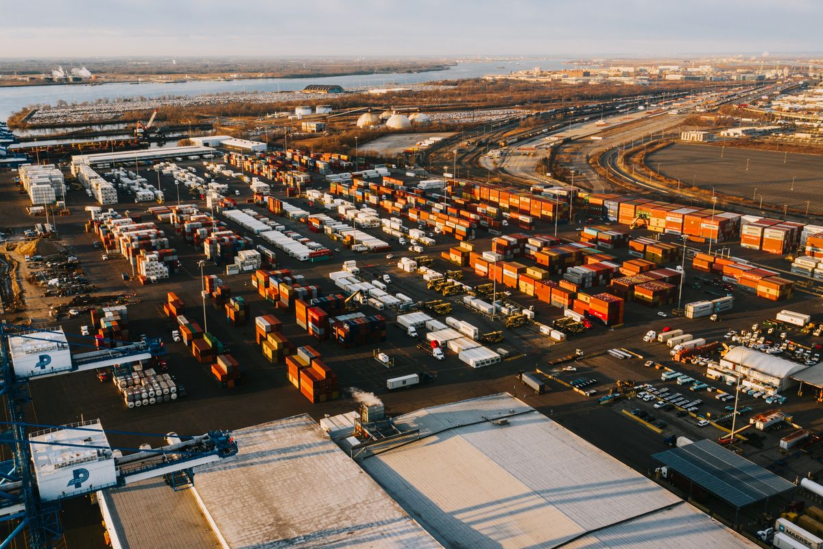 Aerial view of a shipping-container logistics yard at dusk.